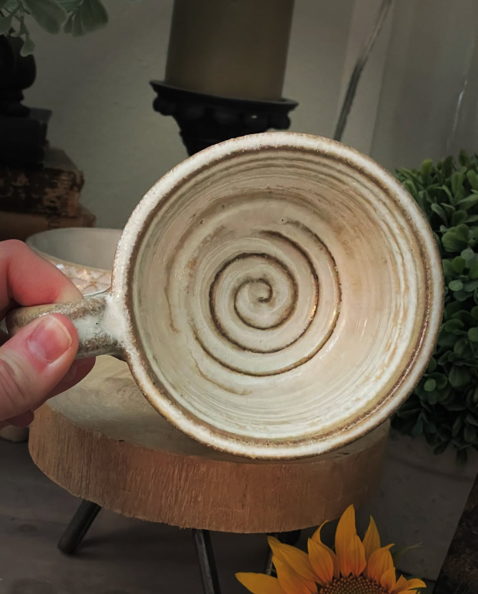 black clay ceramic mug with white glaze and swirl bottom