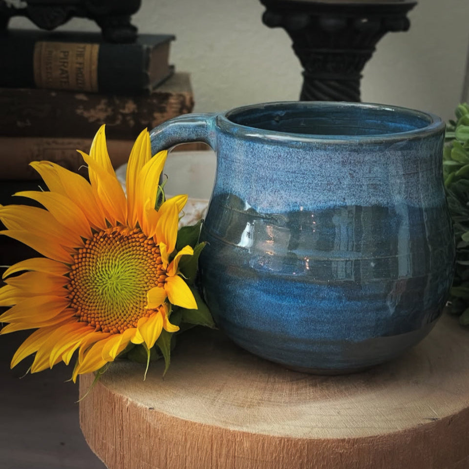 Handmade blue ceramic mug with textured handle and swirled bottom