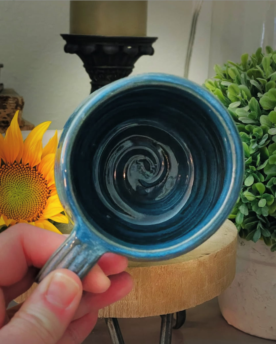 Handmade blue ceramic mug with textured handle and swirled bottom
