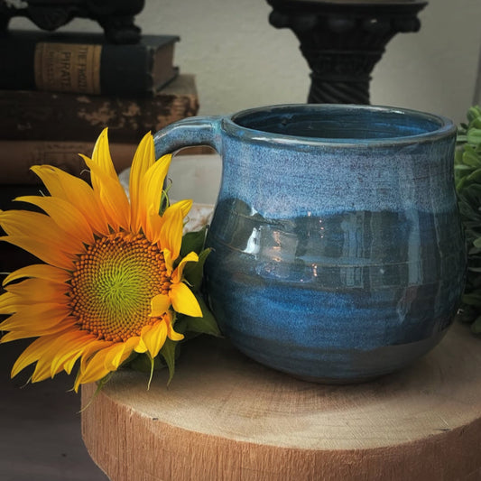 Handmade blue ceramic mug with textured handle and swirled bottom